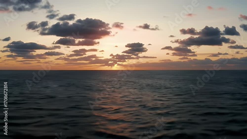 Sunset over a calm sea, with dramatic clouds