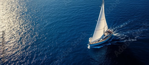 Sailboat Gliding Smoothly Across Bright Blue Ocean Under Warm Sunlight.