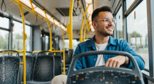 Smiling man travels by bus looking out the window thinking about his day ahead and future plans