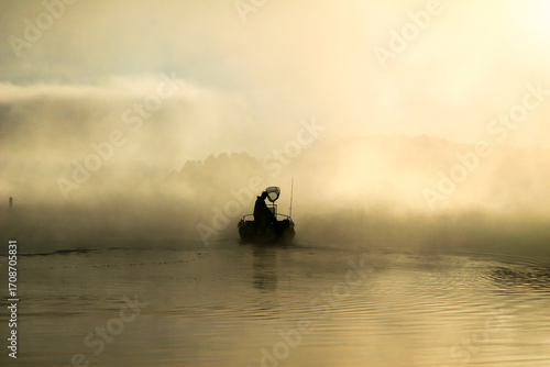 Early morning fisherman with mist on the lake.
