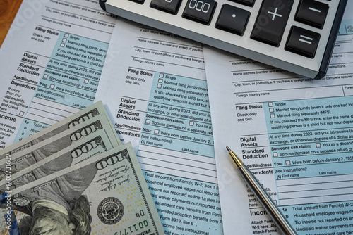 Financial planning with tax forms, cash, and calculator on desk during income reporting season