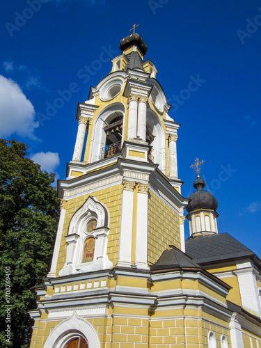 Orthodox church bell tower with bells against blue sky.