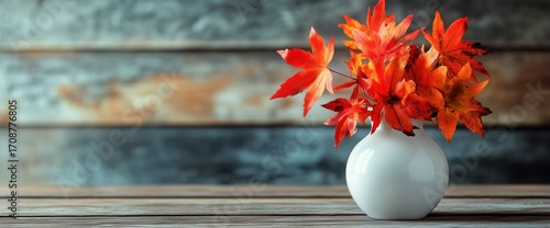 Bright Autumn Leaves in a White Vase on a Wooden Table Against a Rustic Backdrop