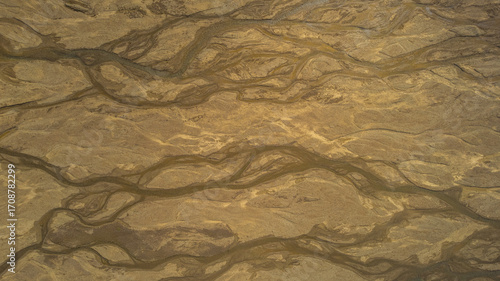 Aerial view of braided river system in Iceland flowing across volcanic sand plains creating abstract natural patterns in the landscape