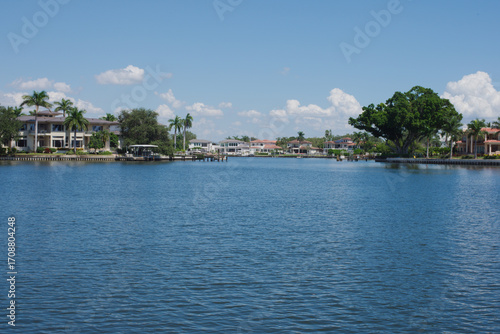 Scenic Coffee Pot Bayou Waterfront Neighborhood with Palm Trees and Luxurious Residences. St. Petersburg, FL. Serene view of a suburban waterfront with upscale homes, lush greenery, and calm waters. 
