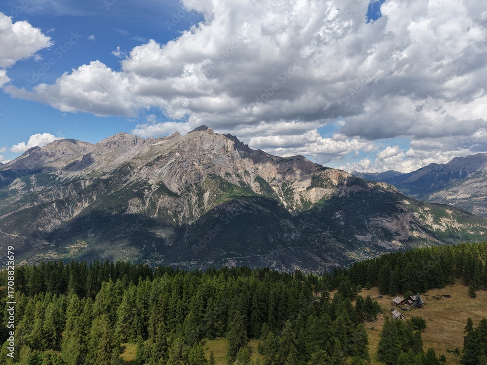 Obraz premium High mountain landscape in the French Alps, forest and rocky peaks near Briançon – Aerial view with chalets