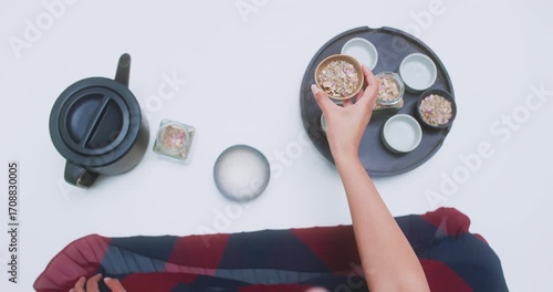 Overhead view of tea tray with woman arranging tea leaves