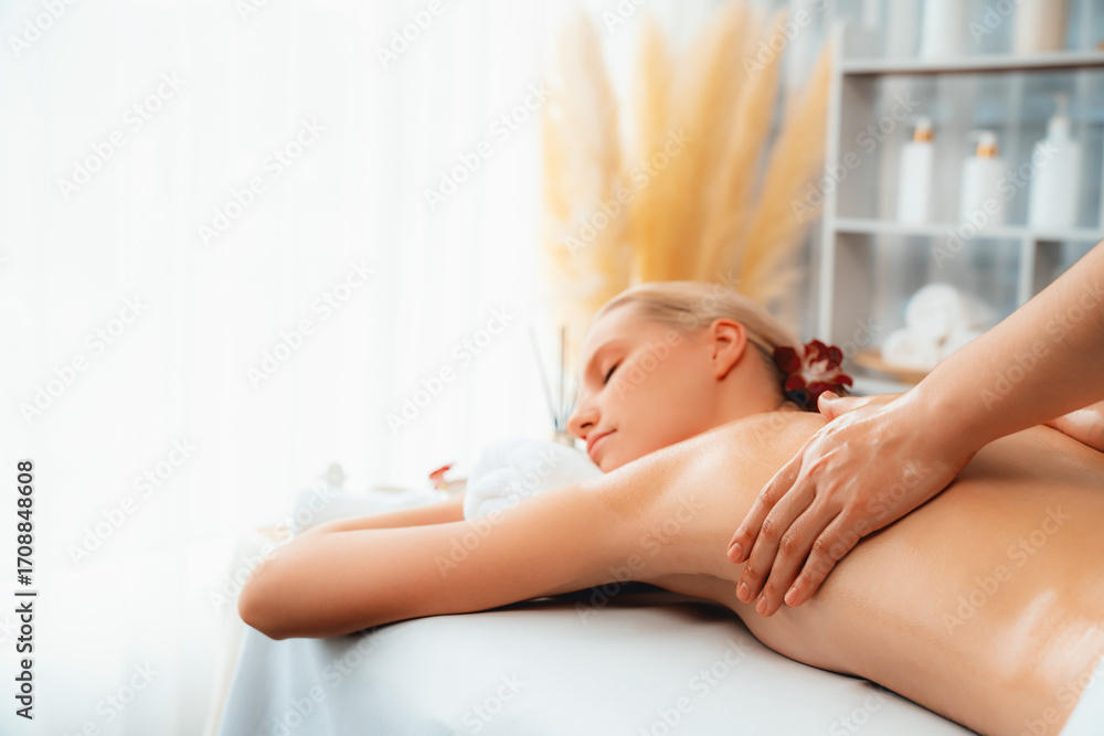 Obraz premium Caucasian woman customer enjoying relaxing anti-stress spa massage and pampering with beauty skin recreation leisure in day light ambient salon spa at luxury resort or hotel. Quiescent