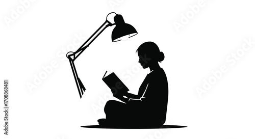Silhouette of a person focused on reading a book under a desk lamp