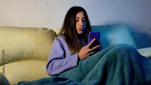 Young woman relaxing on sofa using smartphone and taking selfies