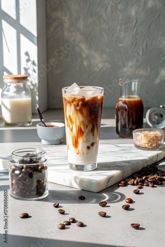 Iced latte in a glass with coffee beans on the table in bright sunlight indoors