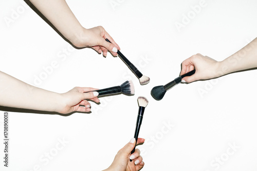 Hands holding various make up beauty brushes for different products 