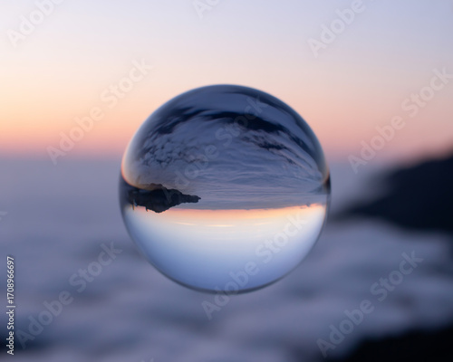 Crystal ball reflecting a beautiful sunset over a sea of clouds landscape