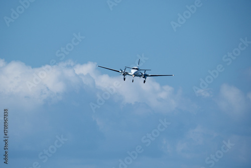 Twin-engine plane in the sky against the clouds. A propeller plane approaches the runway against a backdrop of clouds.