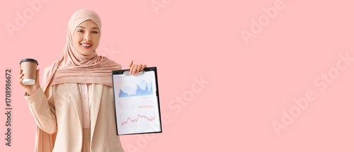 Young Muslim businesswoman with clipboard and coffee cup on pink background