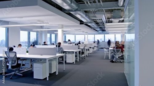 Busy modern office timelapse with blurred people working at computers and walking around