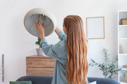 Young woman screwing light ...