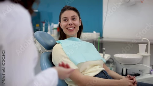 Young female patient sitting in a dental chair listening to a doctor's advice. Professional consultation and treatment plan discussion