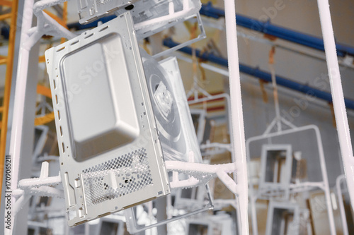 Microwave oven casings on conveyor during washing stage in powder coating workshop