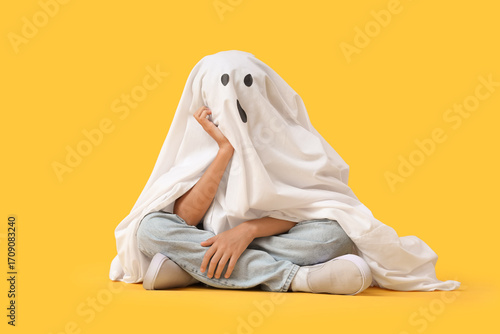 Child in ghost costume sitt...
