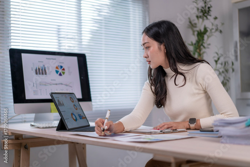 Businesswoman analyzing financial reports and taking notes in modern office