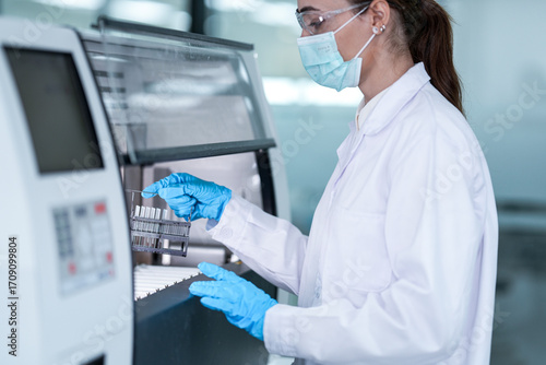 Принти на полотні A medical technician in full PPE loads patient samples into an automated analyzer machine