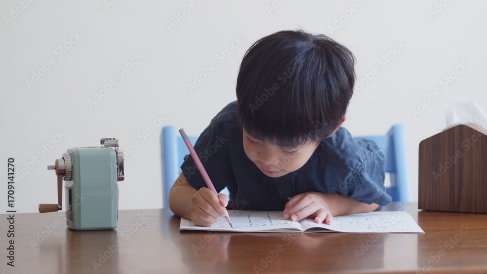 Naklejka premium ひらがなのを書く練習をする5歳の男の子