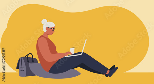Focused senior woman using laptop and drinking coffee while sitting casually. Represents modern older generation, remote work, learning, and digital lifestyle.