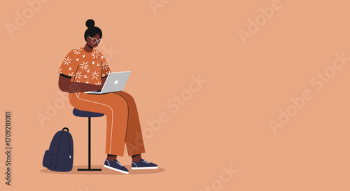 A stylish young Black woman with a bun sits comfortably on a stool, diligently working on her laptop with a backpack nearby, against a warm peach background.
