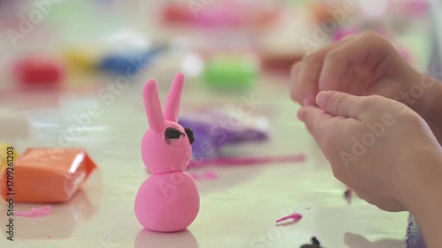 Kids are using clay and colorful play dough to create a pink figure. Children creativity, clay art activity, learning with fun, and early childhood education concept.