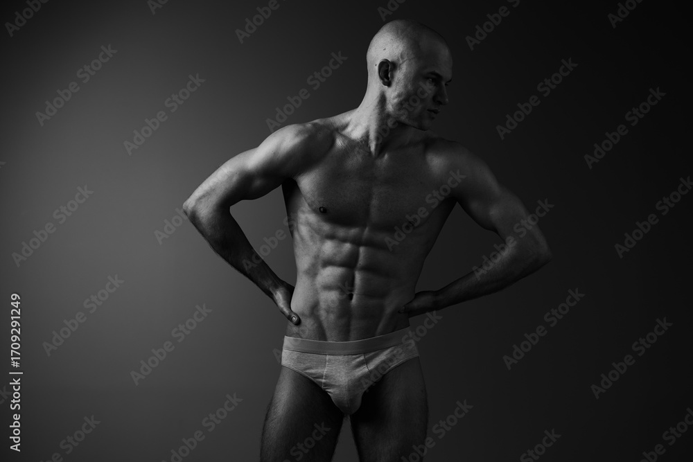 Fototapeta premium Strong man posing in black and white, showcasing athletic physique and confidence, highlighting muscular definition and artistry in form.
