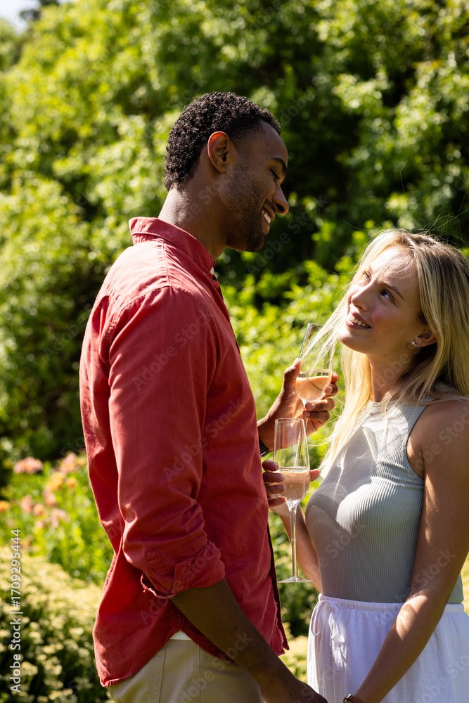 Fototapeta premium Couple enjoying outdoor celebration, smiling and toasting with champagne glasses