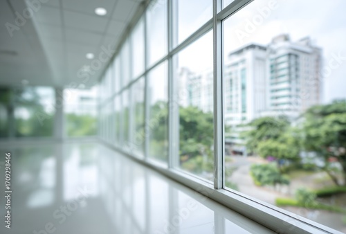 Bright, spacious hallway with large windows, blurring into a cityscape view; light reflecting off the polished floor creates depth