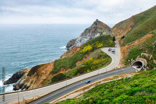 Scenic view of Highway 1 coastline from Gray Whale Cove Trail near Pacifica, California, with ocean waves, rugged cliffs, and lush green hills along the Pacific coast