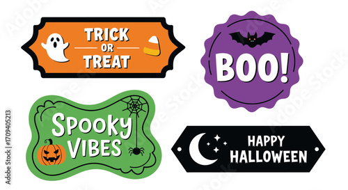 Flat lay of four Halloween themed printable design elements:  'Trick or Treat', 'Boo!', 'Spooky Vibes', and 'Happy Halloween', featuring orange, purple, green, and black