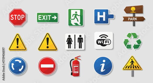 Flat lay of various colorful informational and warning signs against a neutral gray background, showcasing diverse symbols for safety, directions, and facilities.
