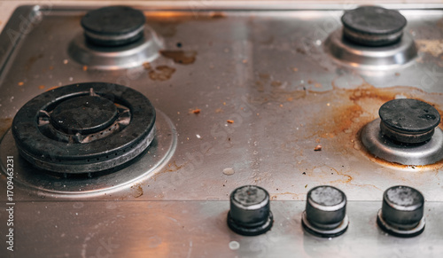Dirty stove with food leftovers. Unclean gas kitchen cooktop with greasy spots, old fat stains, fry spots and oil splatters.