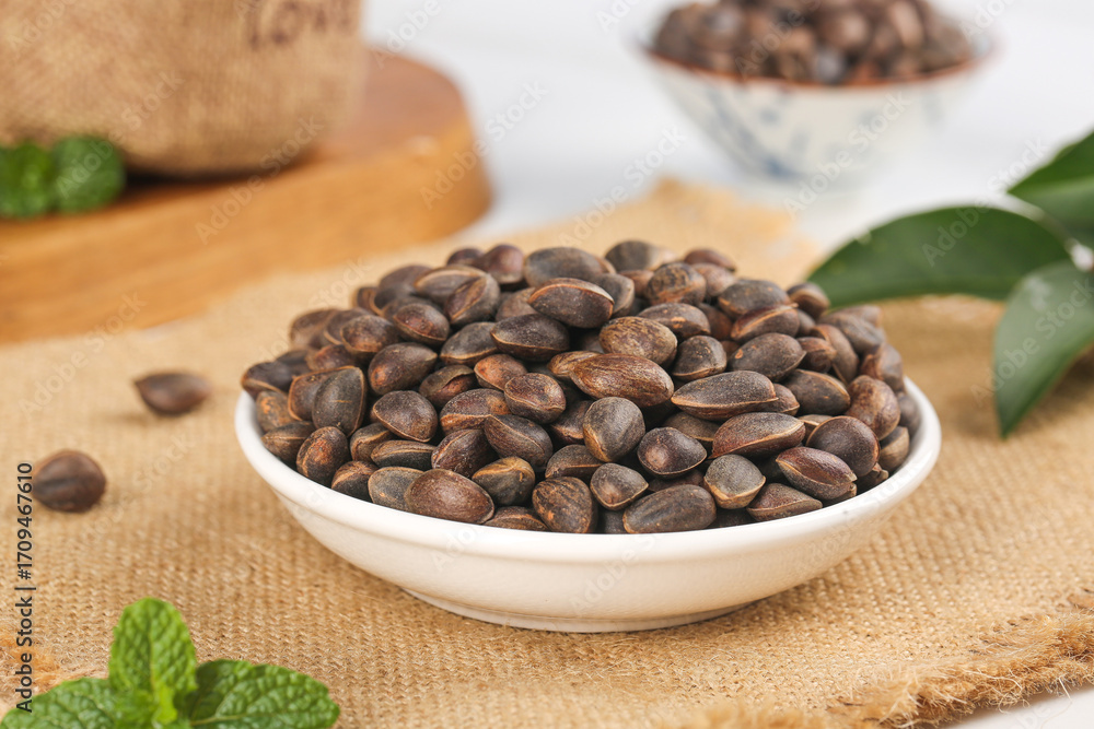 Fototapeta premium Pine Nuts in Bowl on Wooden Board - Wild Mountain Harvesting Natural Healthy Food Ingredient
