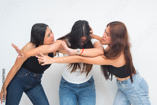 Foto Three young Asian women in a chaotic moment, two fighting and gesturing angrily as one intervenes to separate them, half body shot showing conflict and tension