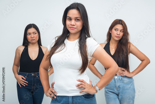 Φωτογραφία A scene with three young Asian women, two casting envious looks toward a poised, confident girl, half body shot highlighting feelings of jealousy and admiration