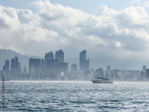 Mist Over Metropolis: Coastal Cityscape with Yacht and Cranes Beneath Moody Skies, Victoria Harbour, Hong Kong
