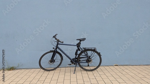 Ein Herrenrad steht an einer blau grauen Wand