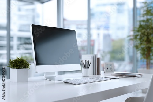 blurred background of a modern office interior with a white desk and computer monitor mockup, a minimalist work space for a graphic designer or web developer, with copy space.