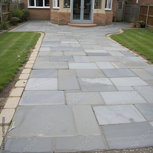 Professional workers laying gray concrete paving slabs in a house courtyard driveway or patio, showcasing.