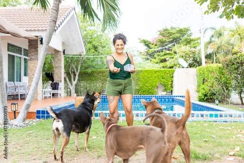 Woman feeding rescued dogs in a garden with swimming pool