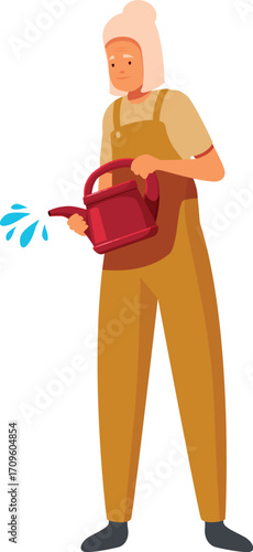 Elderly female farmer in uniform pouring water from watering can, taking care of plants in garden or greenhouse