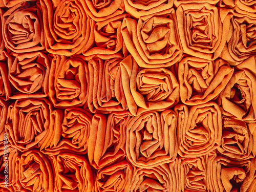 A stack of colorful hijabs or headscarves neatly folded into a square roll. A head covering for Muslim women.