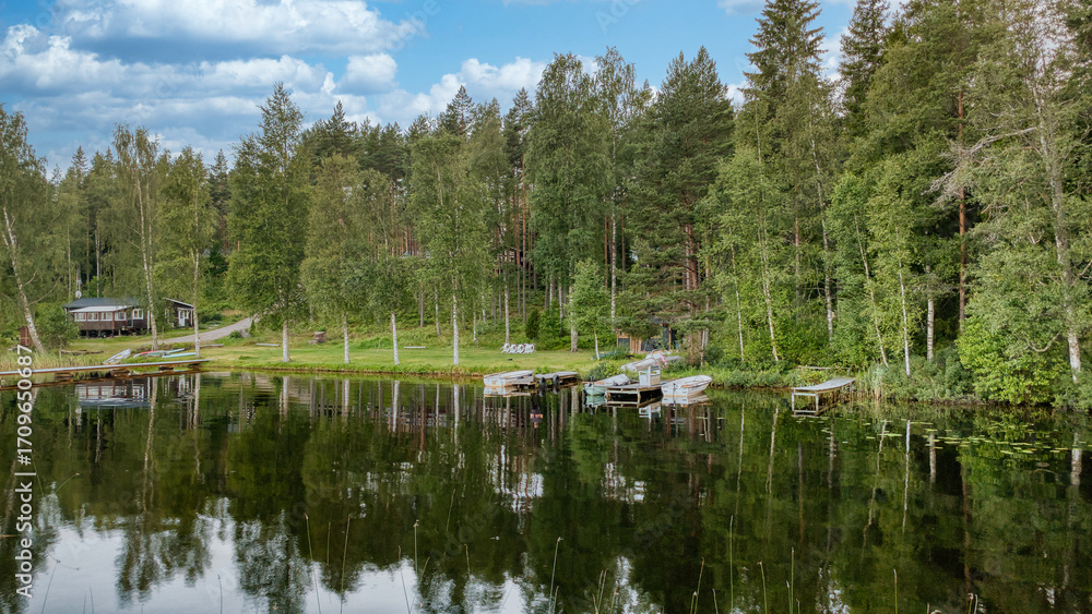 Obraz premium Quiet forest lake with boats and jetties, natural idyll for relaxation & leisure