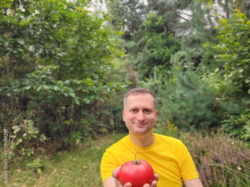 Friendly man holding a fresh red tomato