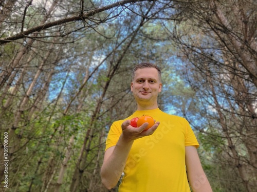 Man holding two tomatoes against a natural background